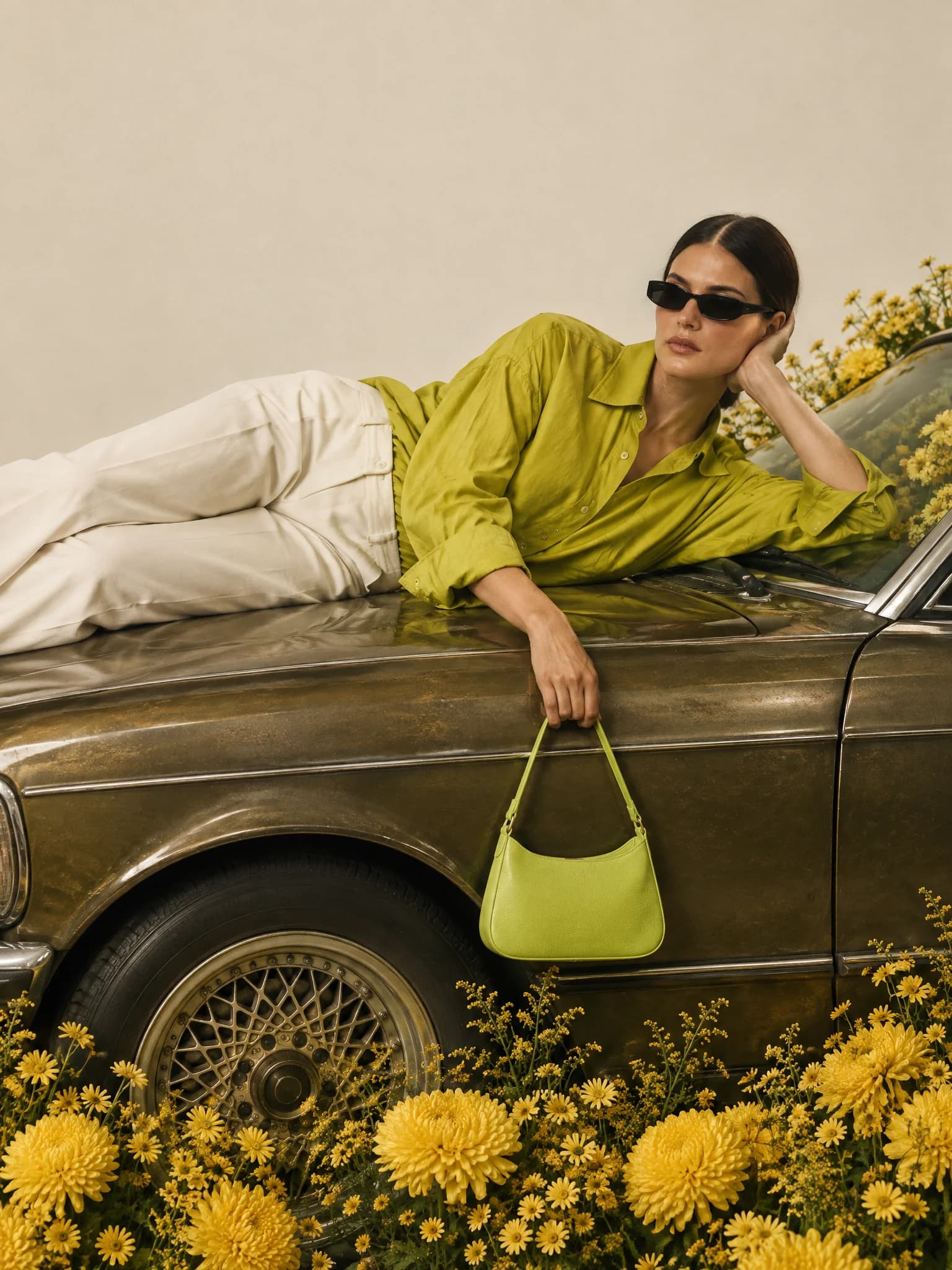 Fashion model with a green handbag on a vintage car