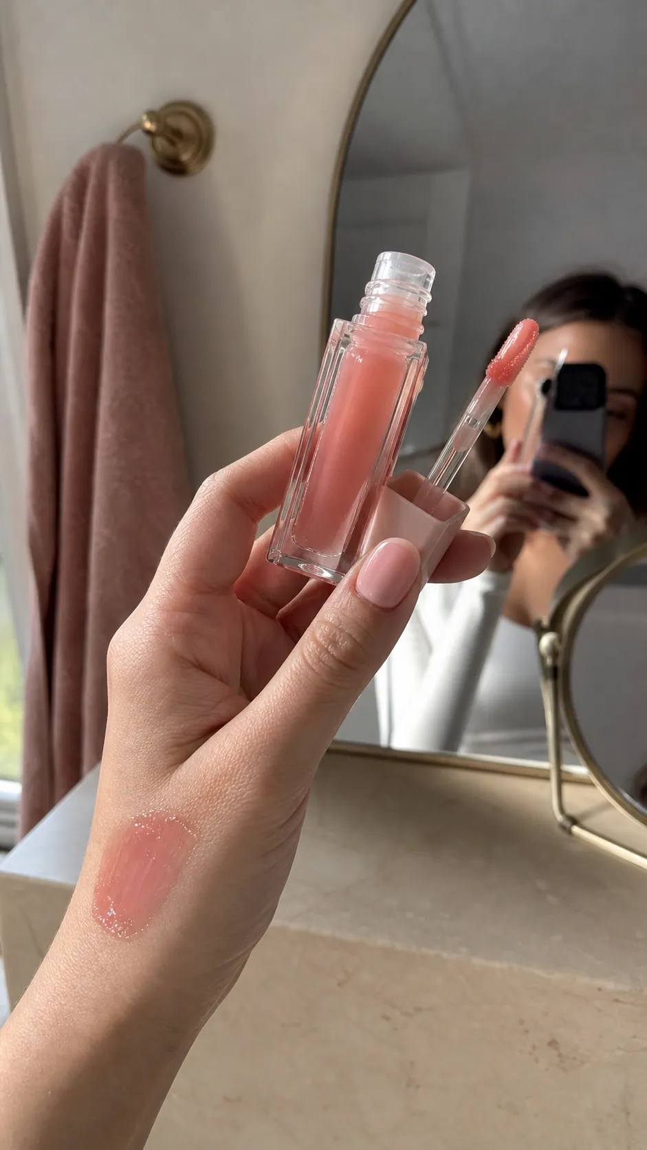Creator filming a lip gloss product in a bathroom mirror